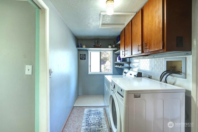 laundry area featuring a textured ceiling, separate washer and dryer, and cabinet space