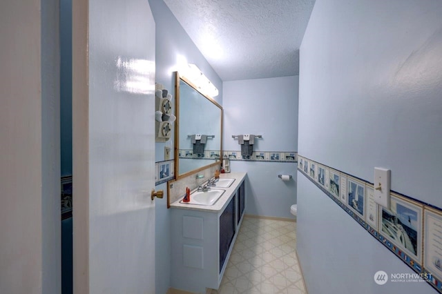 bathroom with toilet, vanity, a textured ceiling, and tile patterned floors