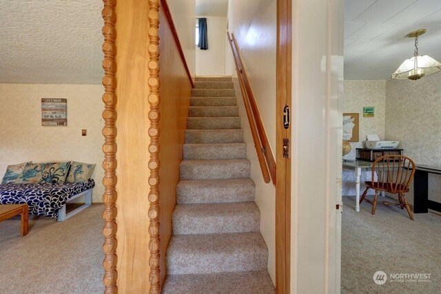 stairs featuring a textured ceiling and carpet flooring