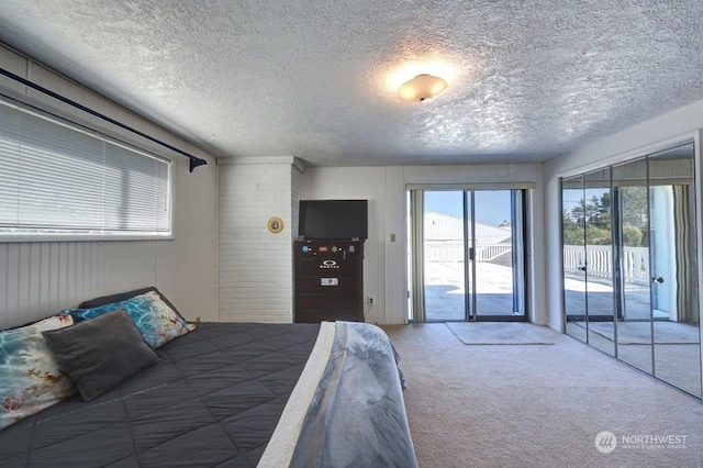 bedroom featuring access to outside, carpet flooring, and a textured ceiling