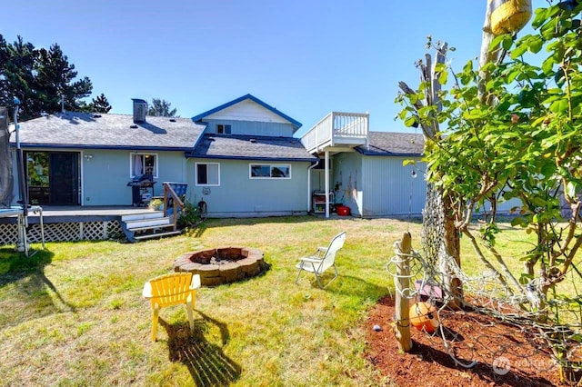 back of house featuring a fire pit, a yard, and a deck