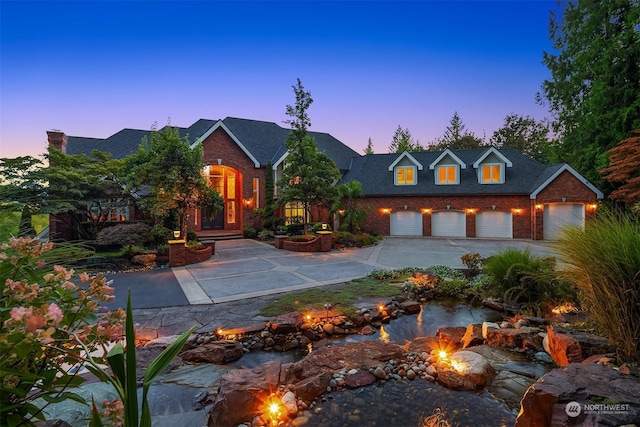 view of front of house featuring brick siding, driveway, and a small pond