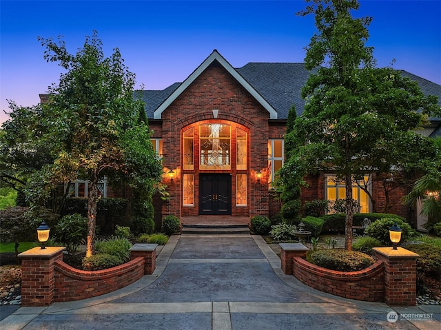 property entrance featuring roof with shingles and brick siding