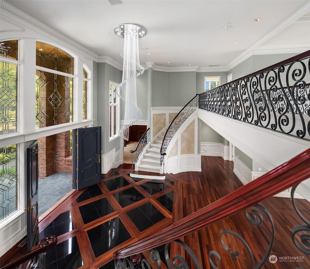 stairs featuring a wainscoted wall, a notable chandelier, crown molding, a decorative wall, and baseboards