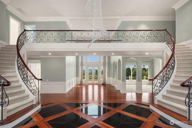 foyer with crown molding, a high ceiling, a decorative wall, and a wealth of natural light