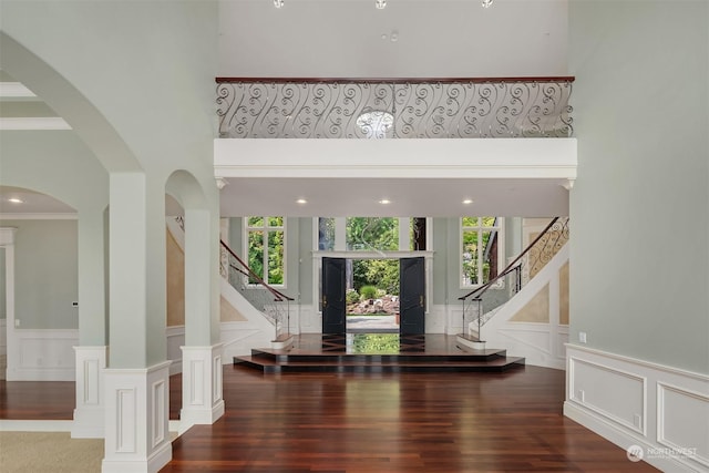 foyer entrance with crown molding, a high ceiling, stairway, and a decorative wall