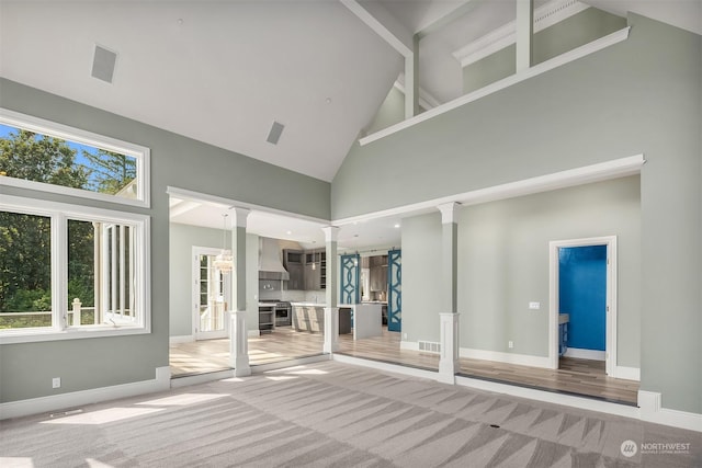 interior space with high vaulted ceiling, plenty of natural light, decorative columns, and baseboards