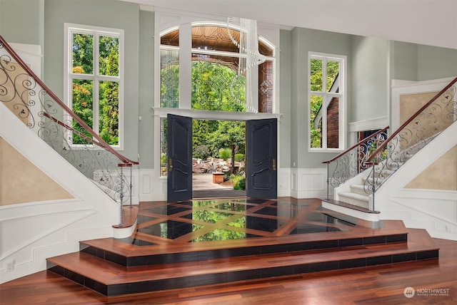 foyer featuring stairs, wainscoting, a wealth of natural light, and a decorative wall