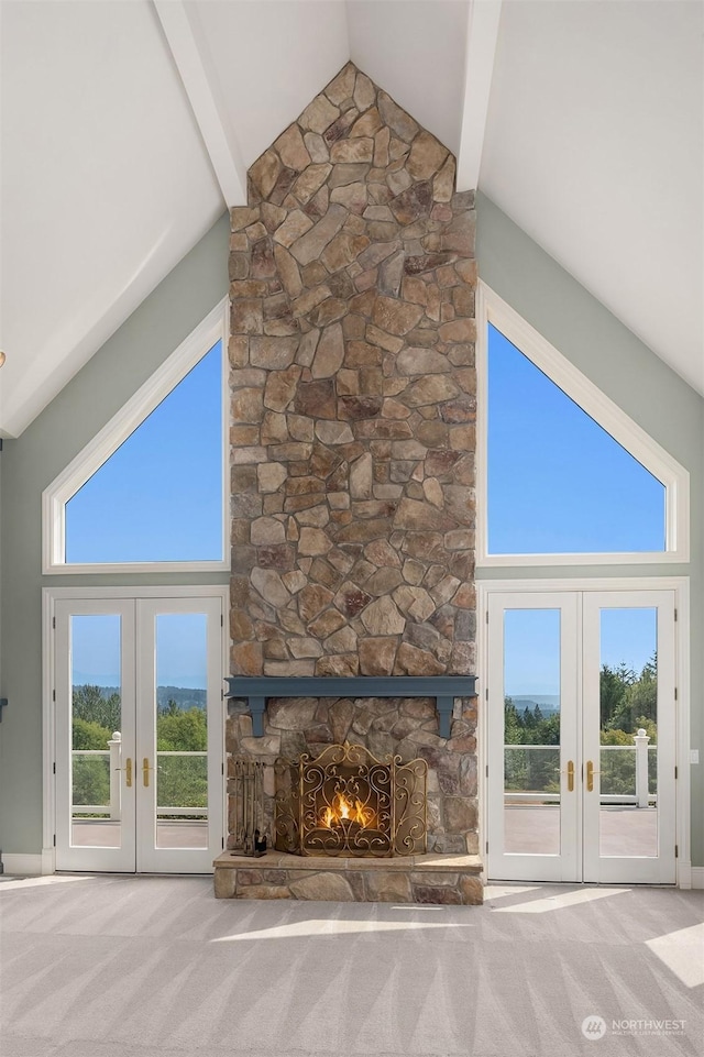 unfurnished living room featuring high vaulted ceiling, french doors, carpet, and a fireplace