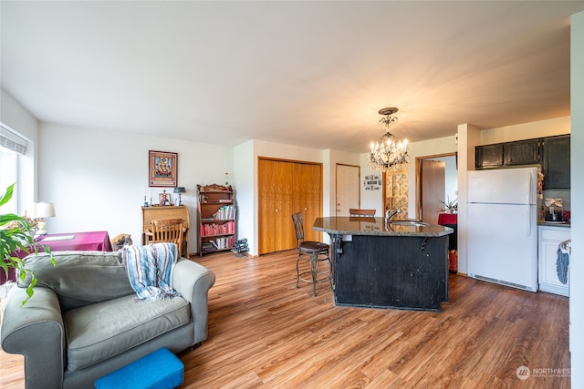 living room featuring wood-type flooring, a chandelier, and sink