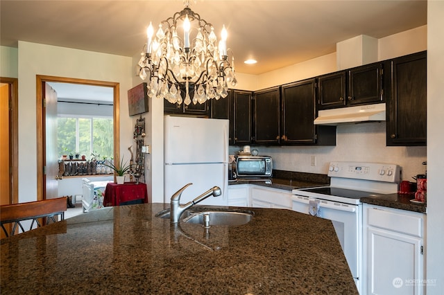 kitchen featuring white appliances, a notable chandelier, hanging light fixtures, sink, and dark stone counters