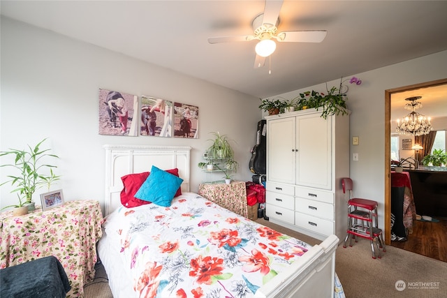 bedroom with ceiling fan with notable chandelier and hardwood / wood-style flooring