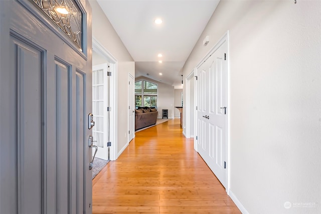 hall with light hardwood / wood-style flooring and vaulted ceiling