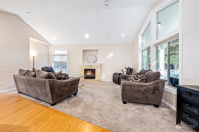 living room featuring hardwood / wood-style floors, a high end fireplace, and vaulted ceiling