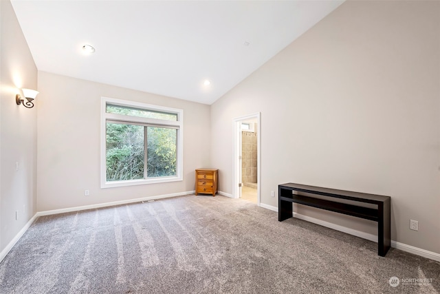 carpeted spare room featuring high vaulted ceiling