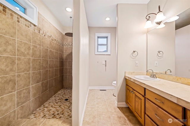 bathroom featuring tile patterned flooring, toilet, vanity, and tiled shower