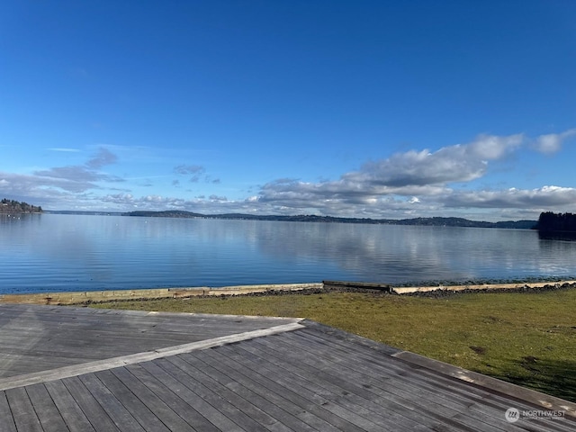 view of dock with a water view and a yard