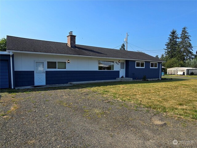single story home featuring a shingled roof, a chimney, and a front lawn