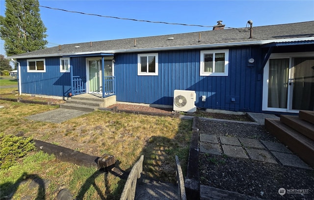 rear view of property with ac unit, a shingled roof, and a chimney