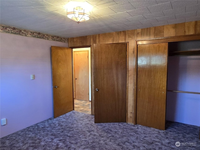 unfurnished bedroom featuring carpet floors and wooden walls