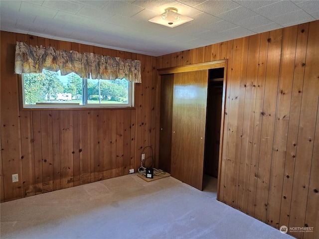 unfurnished bedroom with wood walls, a closet, and carpet flooring