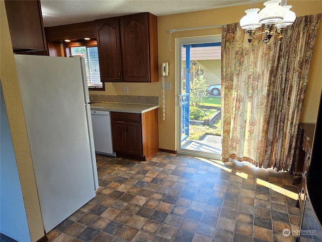 kitchen featuring white appliances, an inviting chandelier, and hanging light fixtures