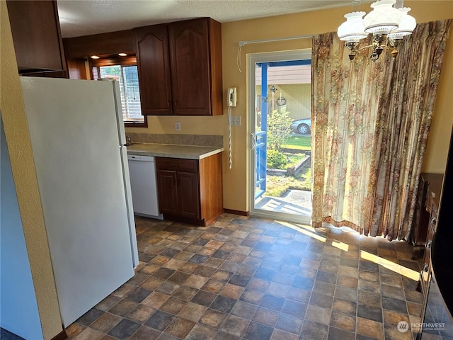 kitchen featuring white appliances, stone finish flooring, light countertops, and a notable chandelier