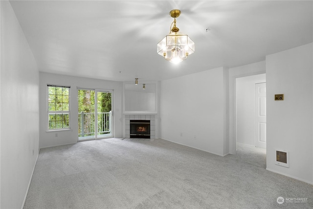 unfurnished living room featuring baseboards, a chandelier, a tiled fireplace, carpet floors, and visible vents