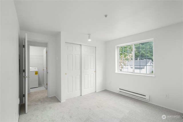 unfurnished bedroom with light colored carpet, baseboard heating, washer / clothes dryer, and a closet