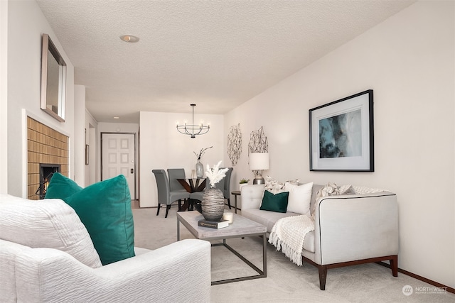 carpeted living room with a fireplace, a notable chandelier, and a textured ceiling