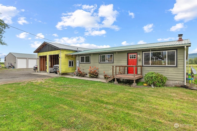 view of front of house featuring a garage, metal roof, a front lawn, and an outdoor structure