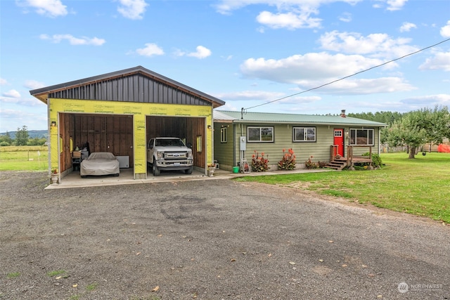 view of front facade with a garage, metal roof, and a front yard