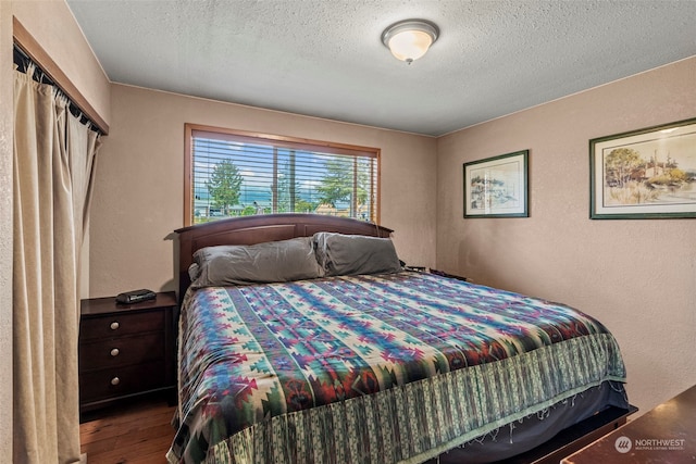 bedroom featuring a textured wall, a textured ceiling, and wood finished floors