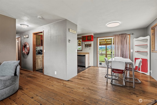 dining room with wood-type flooring and a textured wall