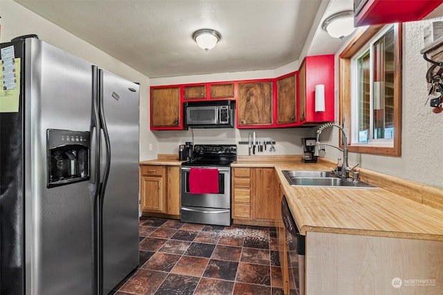 kitchen with stainless steel appliances, stone finish floor, light countertops, and a sink