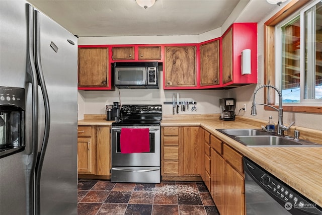 kitchen with stone finish flooring, stainless steel appliances, a sink, and light countertops