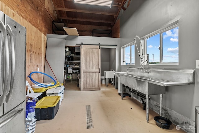 basement featuring a barn door and freestanding refrigerator