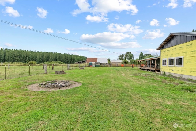 view of yard with a fire pit, fence, and a rural view