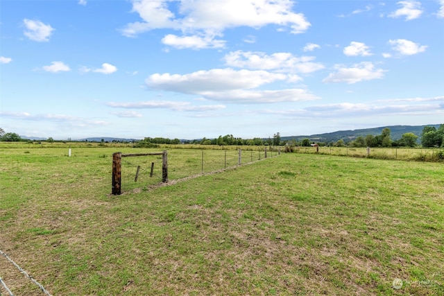 view of yard with fence and a rural view