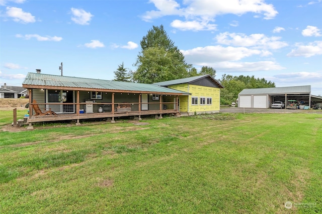 rear view of property featuring a garage, metal roof, a yard, and an outdoor structure