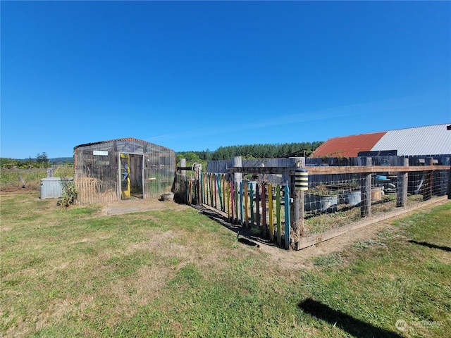 view of yard with a garden, an outdoor structure, and fence