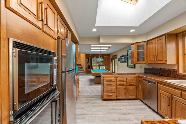 kitchen featuring light wood-type flooring, billiards, stainless steel appliances, kitchen peninsula, and hanging light fixtures