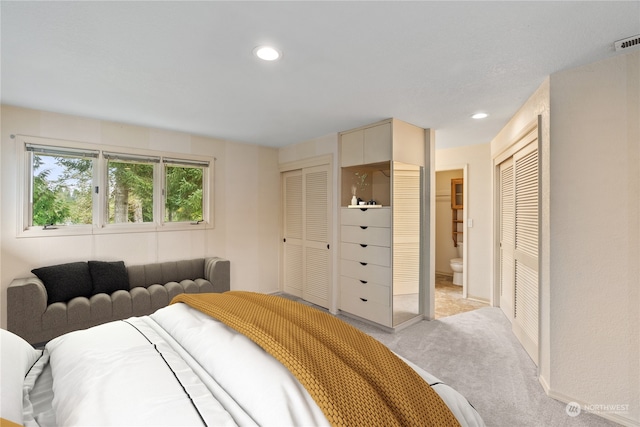 carpeted bedroom with connected bathroom and multiple closets