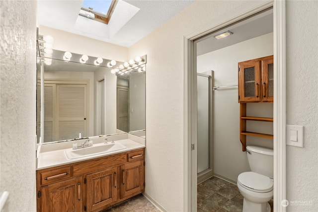 bathroom featuring toilet, walk in shower, vanity, a textured ceiling, and a skylight