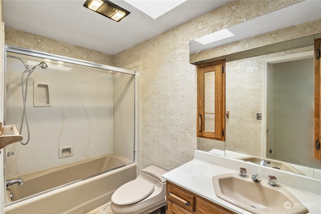 full bathroom featuring vanity, toilet, bath / shower combo with glass door, and a skylight