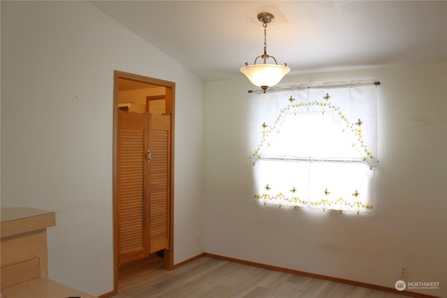 empty room with light hardwood / wood-style floors and lofted ceiling