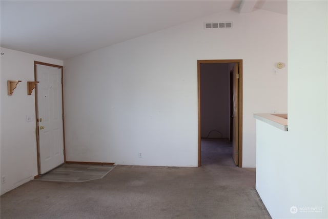 empty room featuring light colored carpet and lofted ceiling with beams