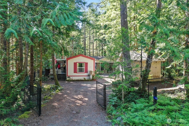 exterior space featuring a gate, fence, and a view of trees