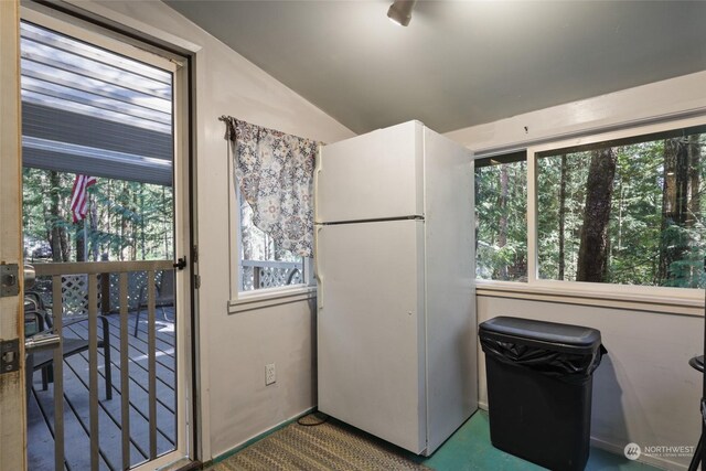 kitchen with a wealth of natural light, freestanding refrigerator, and lofted ceiling