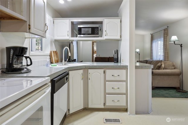 kitchen with stainless steel appliances, sink, light carpet, and white cabinetry